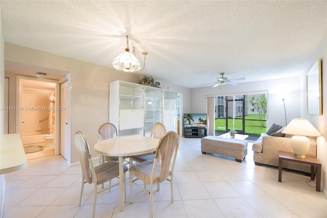 tiled dining room with ceiling fan with notable chandelier and a textured ceiling