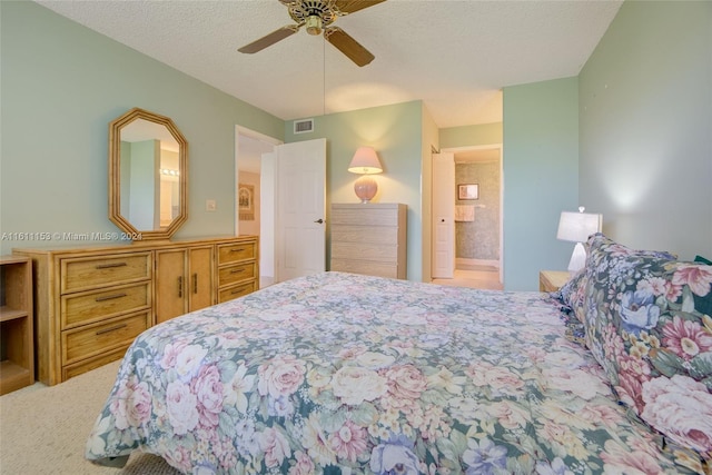 bedroom with a textured ceiling, carpet flooring, ensuite bath, and ceiling fan