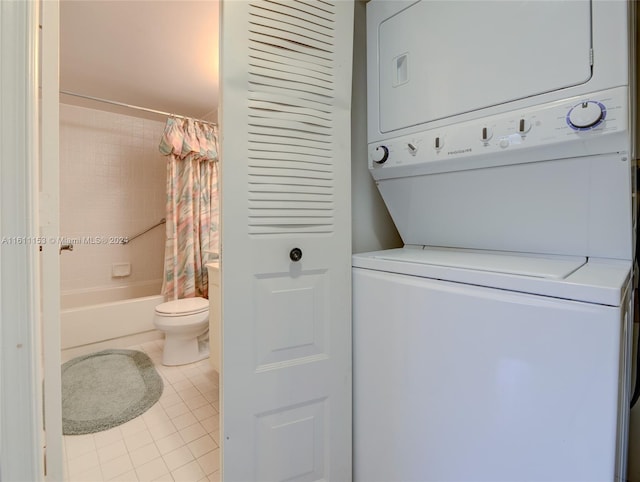 laundry area featuring stacked washer / drying machine and light tile patterned floors