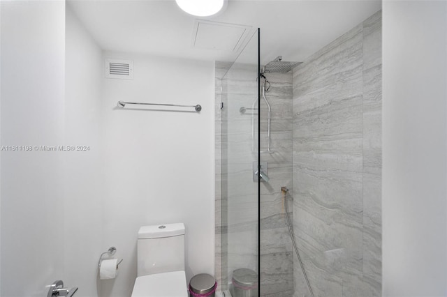 bathroom featuring tiled shower and toilet