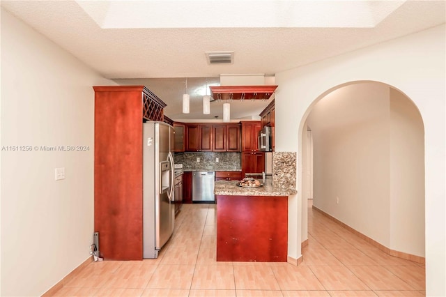 kitchen with kitchen peninsula, stainless steel appliances, decorative backsplash, light tile patterned flooring, and a textured ceiling