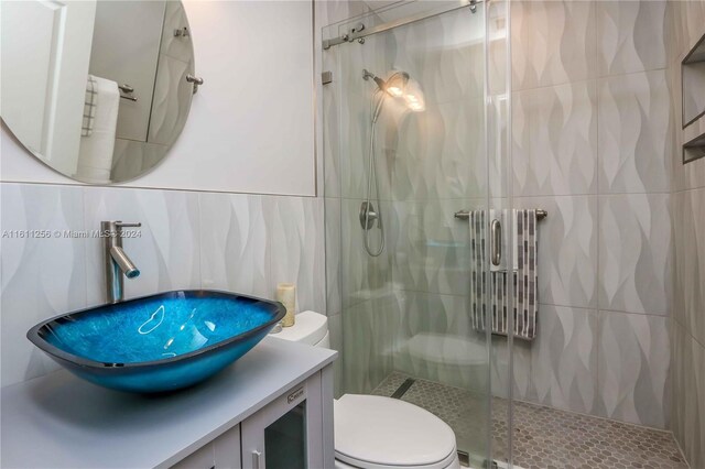 bathroom with toilet, vanity, tile walls, and walk in shower