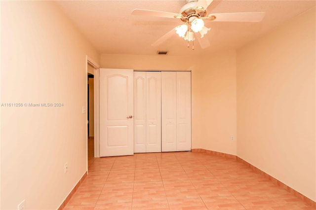 unfurnished bedroom with ceiling fan, light tile patterned floors, and a closet