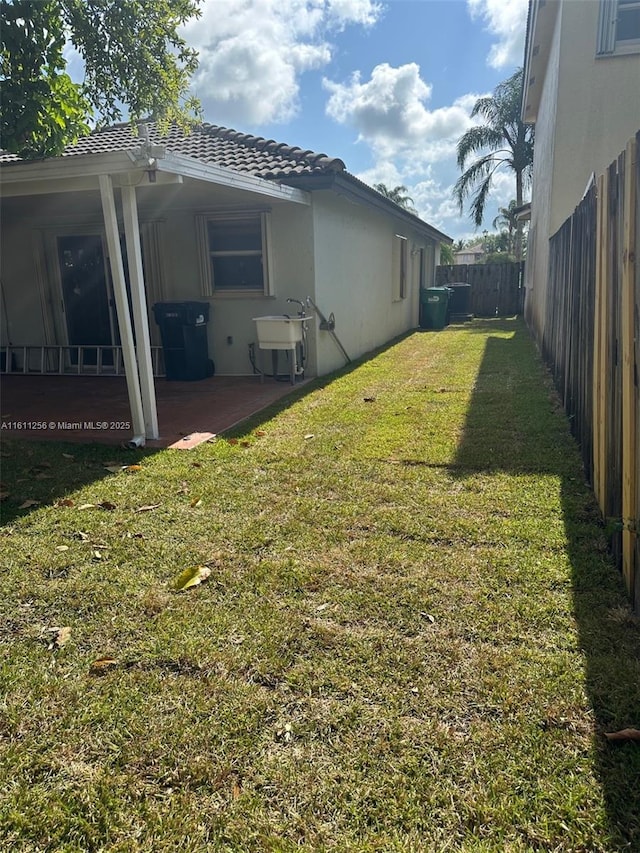 21532 SW 88th Pl, Cutler Bay, FL 33189 - view of property exterior with stucco siding, a fenced backyard, a lawn, a sink, and a patio