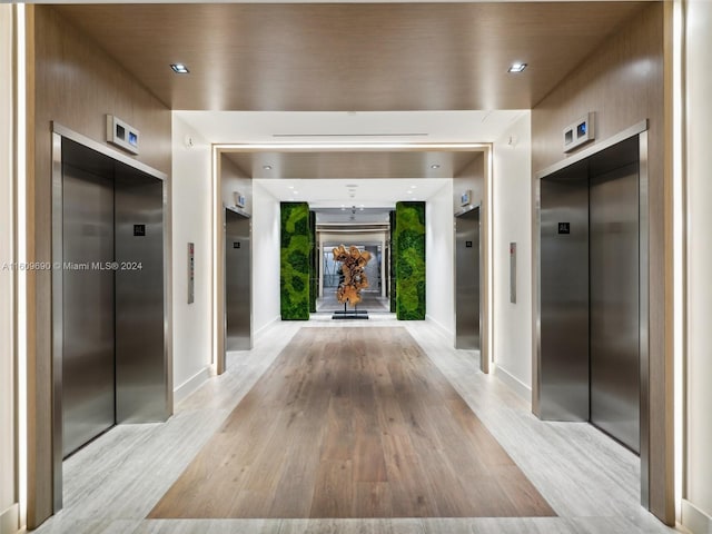 corridor featuring light wood-type flooring and elevator