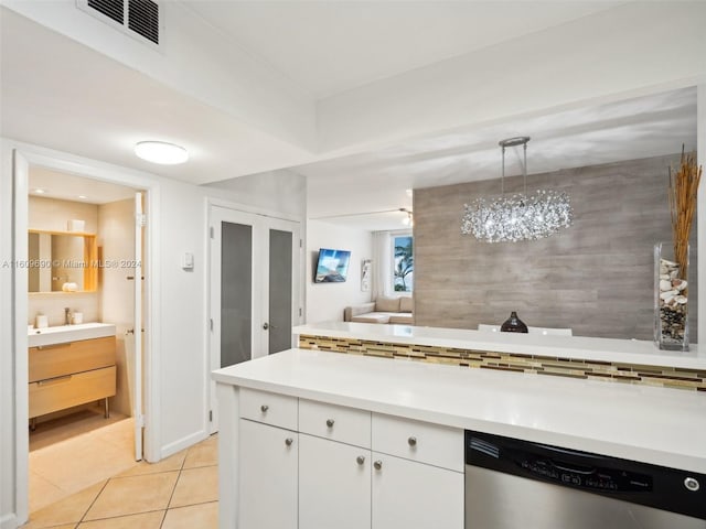 kitchen with white cabinets, light tile patterned floors, stainless steel dishwasher, and hanging light fixtures