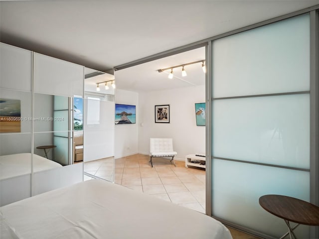 bedroom featuring light tile patterned floors, rail lighting, and a closet