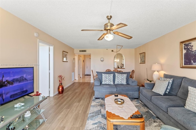 living room featuring light hardwood / wood-style floors, a textured ceiling, and ceiling fan