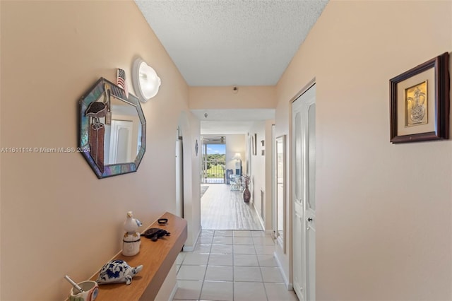 hallway featuring a textured ceiling and light tile patterned flooring