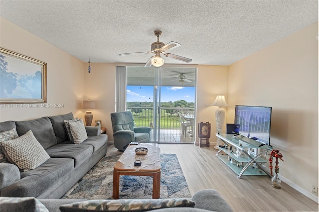 living room with a textured ceiling, light hardwood / wood-style floors, and ceiling fan