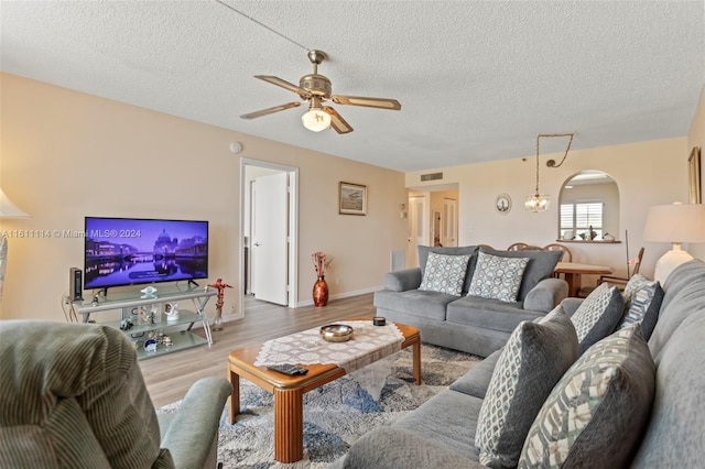 living room with a textured ceiling, light hardwood / wood-style flooring, and ceiling fan with notable chandelier