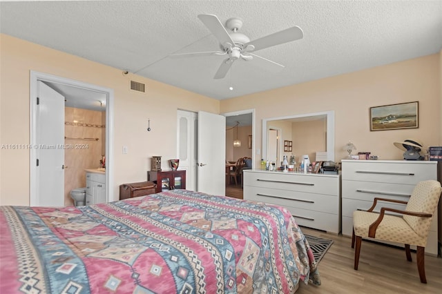 bedroom featuring light hardwood / wood-style flooring, a textured ceiling, ensuite bathroom, and ceiling fan