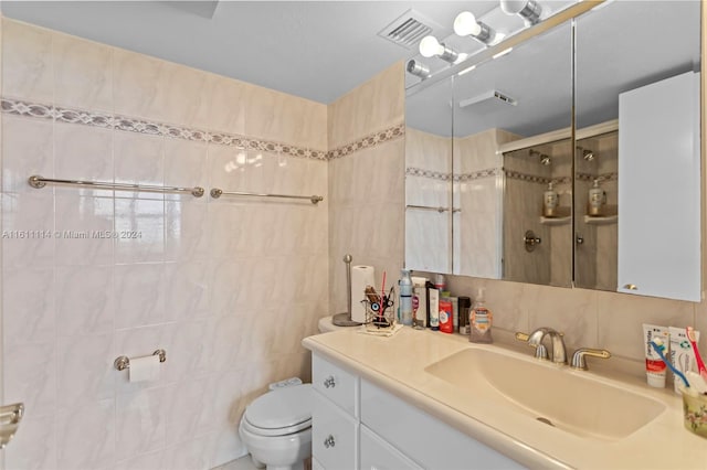 bathroom featuring tile walls, vanity, a shower with shower door, and toilet