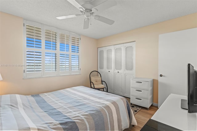 bedroom featuring light hardwood / wood-style flooring, a textured ceiling, a closet, and ceiling fan