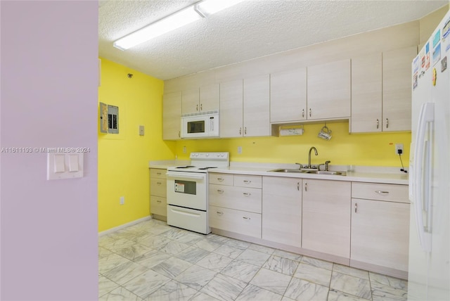 kitchen with white appliances, sink, light tile floors, and a textured ceiling