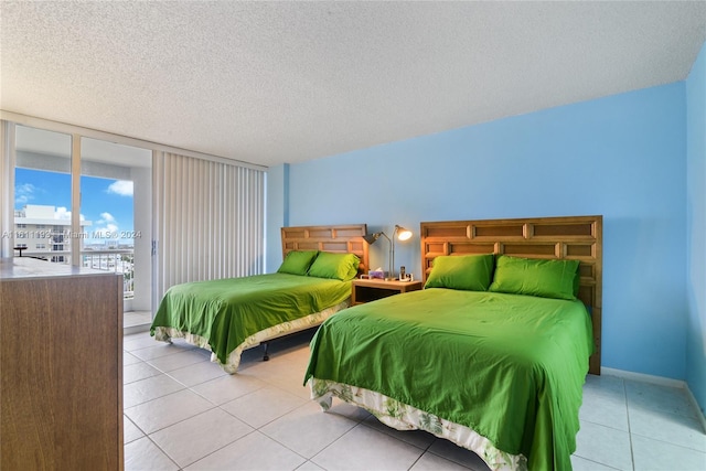 bedroom with floor to ceiling windows, light tile flooring, a textured ceiling, and access to outside