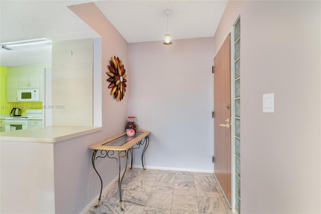 hall with a textured ceiling and light tile floors