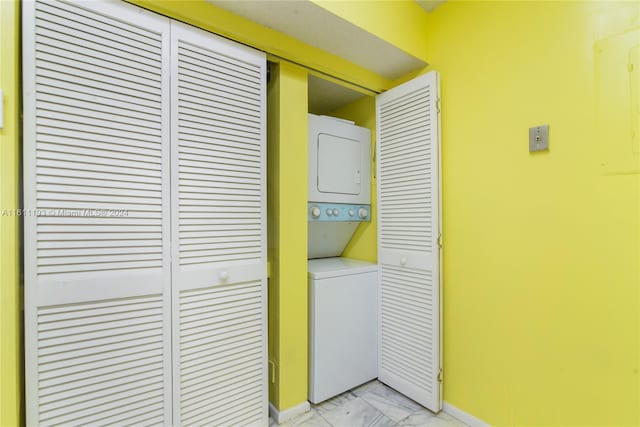 laundry room with stacked washer and clothes dryer and light tile floors