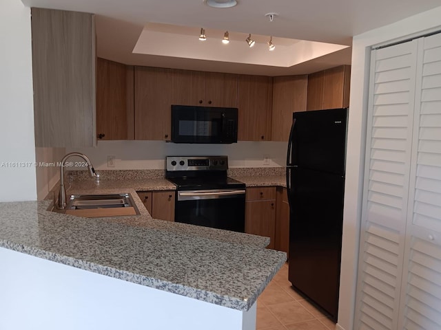 kitchen featuring light stone countertops, sink, kitchen peninsula, and black appliances