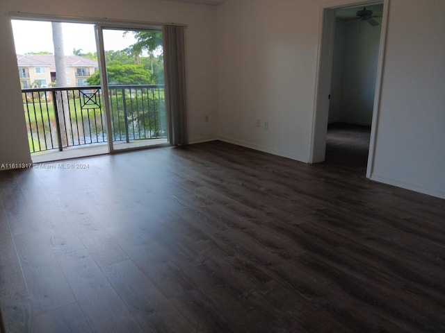 spare room featuring ceiling fan, dark hardwood / wood-style flooring, and a water view