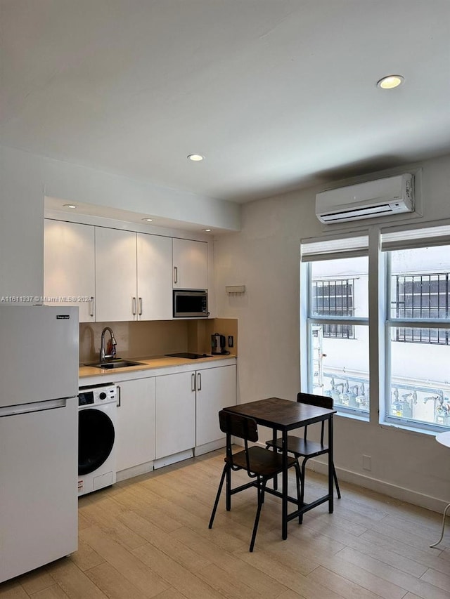 kitchen featuring white cabinetry, washer / dryer, a wall mounted AC, white refrigerator, and light hardwood / wood-style floors