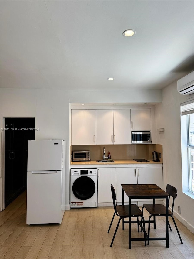 kitchen with stainless steel microwave, washer / clothes dryer, white cabinetry, sink, and white fridge