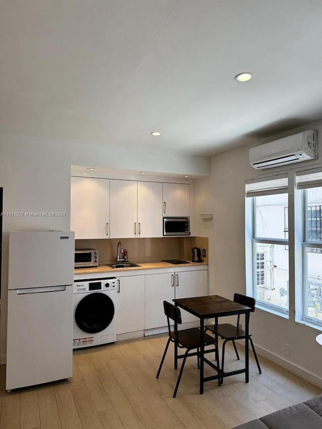 kitchen with sink, white cabinetry, a wall mounted air conditioner, white fridge, and washer / clothes dryer