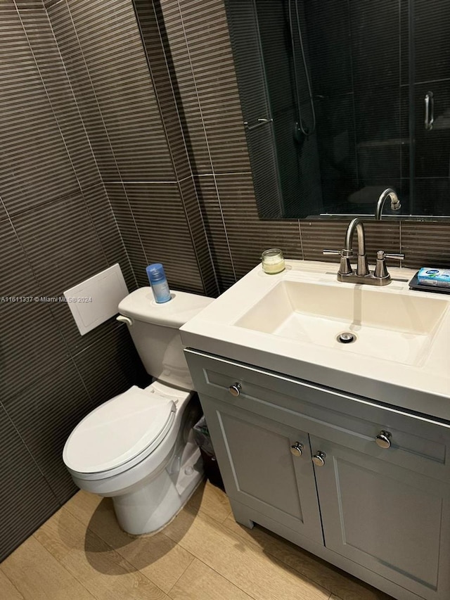 bathroom featuring vanity, tile walls, and toilet