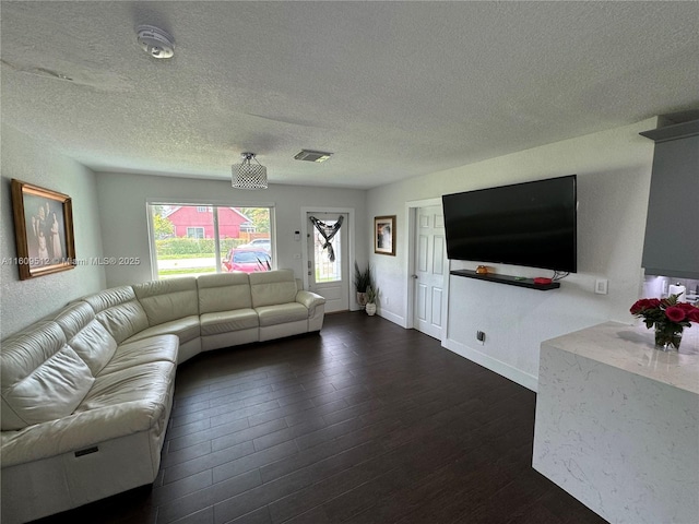 living room featuring dark wood-type flooring, visible vents, baseboards, and a textured ceiling