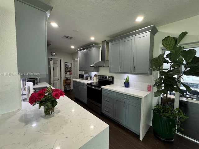 kitchen featuring a textured ceiling, appliances with stainless steel finishes, wall chimney exhaust hood, and gray cabinets