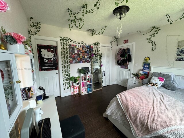 bedroom with a textured ceiling and dark hardwood / wood-style floors