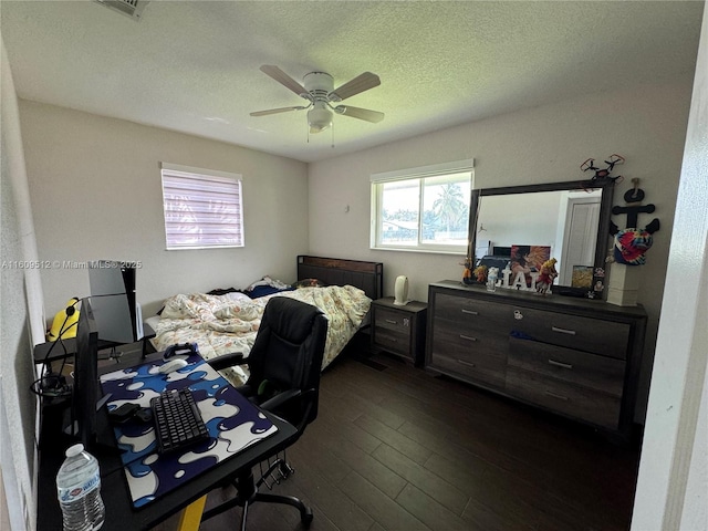 bedroom with ceiling fan, dark wood-type flooring, and a textured ceiling