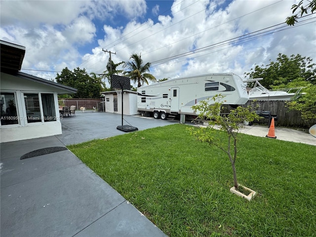 view of yard featuring a patio area, fence, and an outdoor structure
