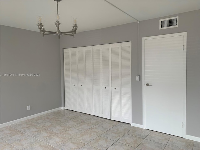 unfurnished bedroom featuring a chandelier, a closet, and light tile patterned flooring