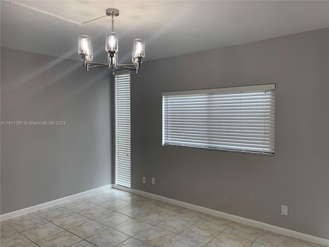 unfurnished room with an inviting chandelier and light tile patterned floors