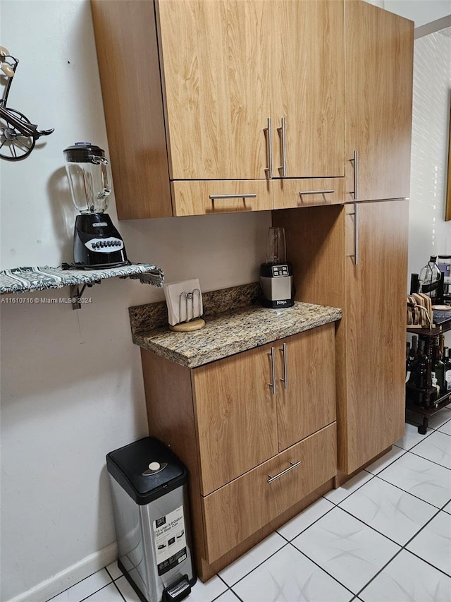 kitchen with light tile patterned floors and dark stone counters