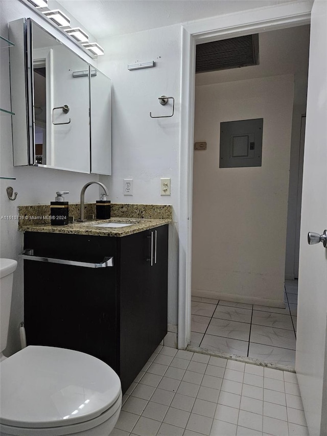 bathroom featuring tile patterned floors, vanity, electric panel, and toilet