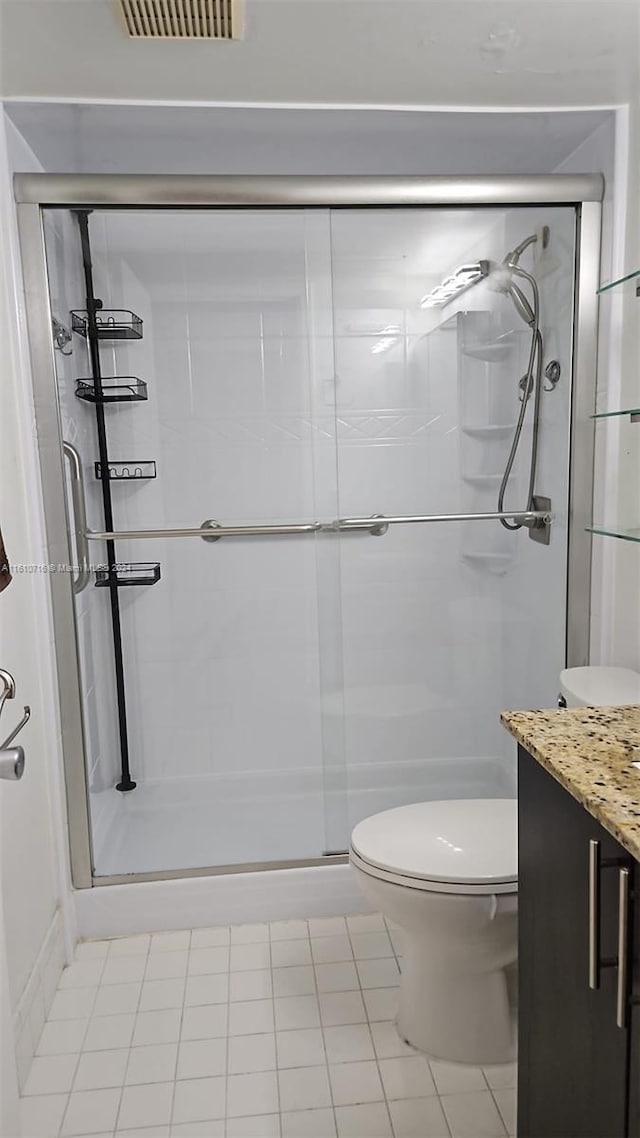 bathroom featuring tile patterned flooring, vanity, toilet, and walk in shower