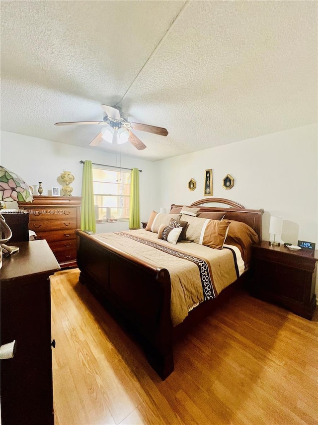 bedroom with ceiling fan, light hardwood / wood-style floors, and a textured ceiling