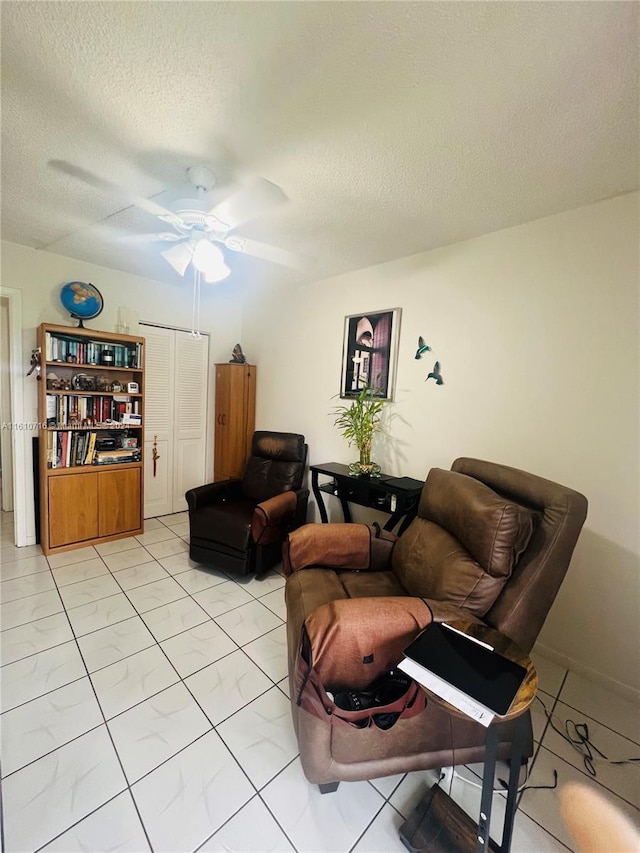 living room with ceiling fan and a textured ceiling