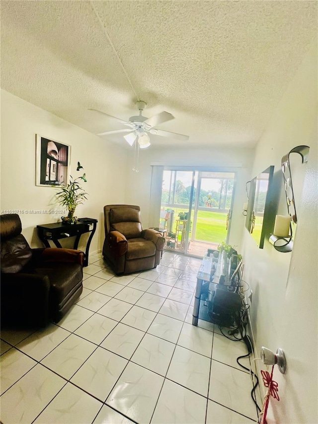 living room with ceiling fan, light tile patterned flooring, and a textured ceiling