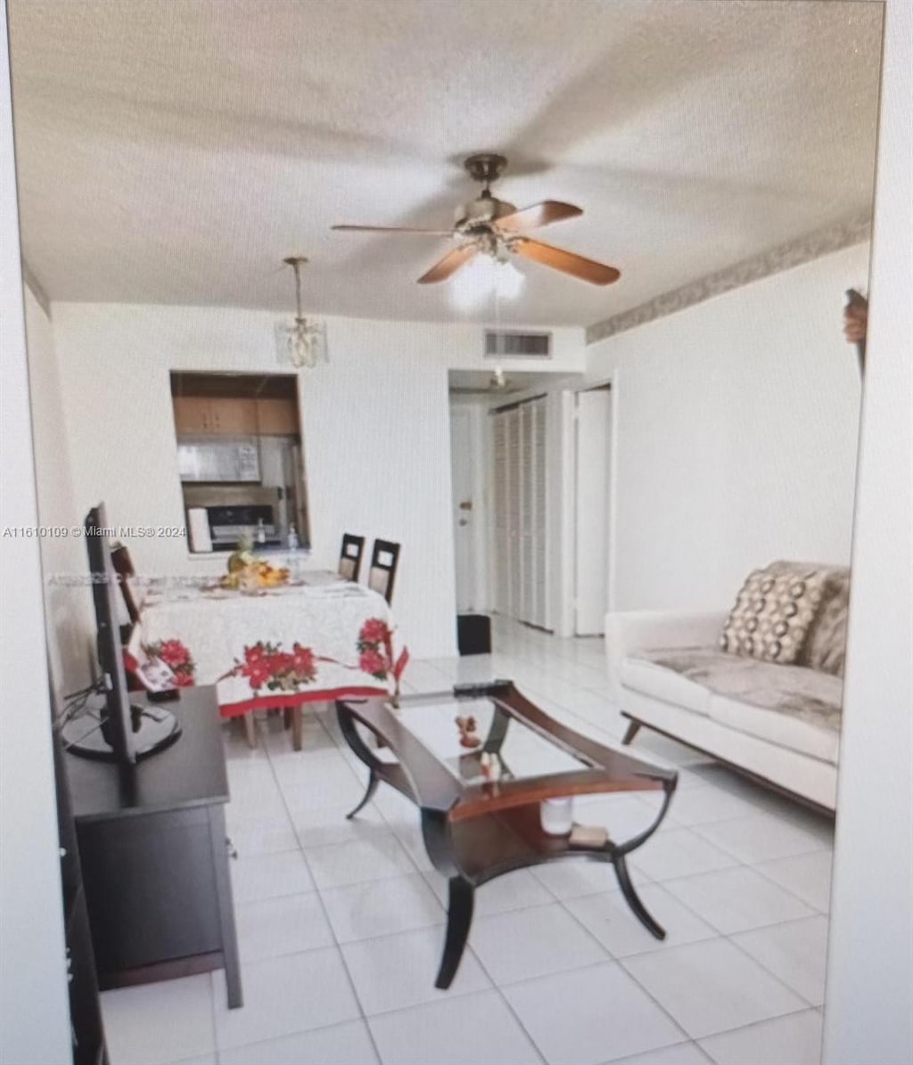 tiled living room with ceiling fan and a textured ceiling