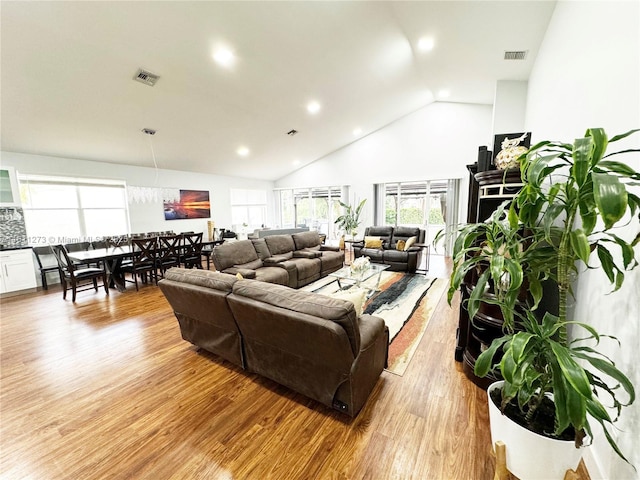 living room with high vaulted ceiling, wood finished floors, and visible vents