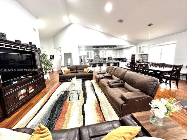 living area featuring high vaulted ceiling, visible vents, and wood finished floors