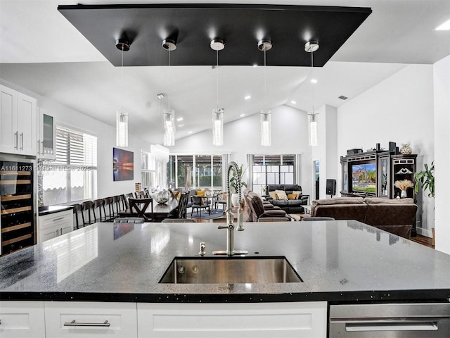 kitchen featuring an island with sink, white cabinets, open floor plan, and a sink