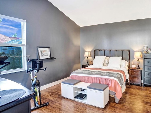 bedroom featuring vaulted ceiling, baseboards, and wood finished floors