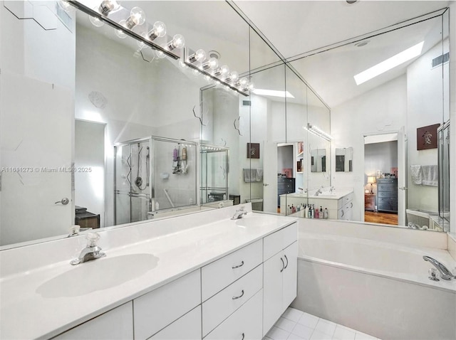 bathroom with double vanity, vaulted ceiling with skylight, a bath, a shower stall, and a sink