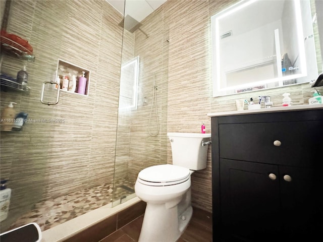 full bath featuring toilet, walk in shower, tile walls, and vanity