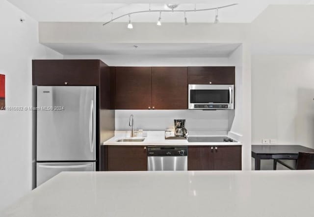 kitchen featuring light countertops, appliances with stainless steel finishes, a sink, and dark brown cabinetry