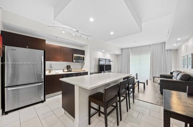 kitchen with a center island, appliances with stainless steel finishes, a breakfast bar area, dark brown cabinetry, and sink